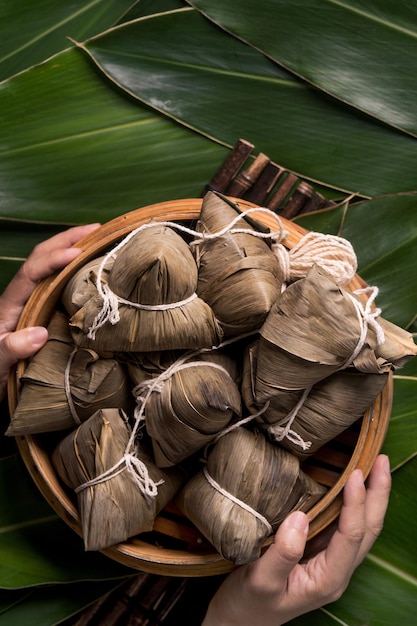 Rice dumpling zongzi traditional chinese food on green leaf\
background of dragon boat festival duanwu festival top view flat\
lay design concept