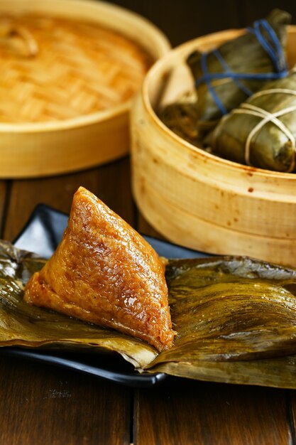 Photo rice dumplings zongzi and bamboo steamer on wooden table