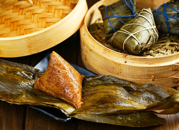 Rice dumplings zongzi and bamboo steamer on wooden table