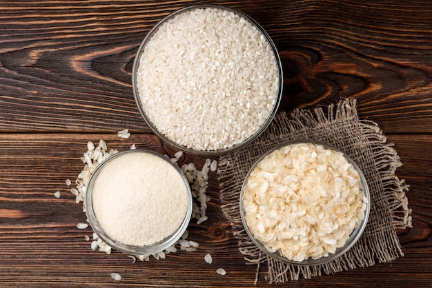 Rice flakes and flour on dark wooden