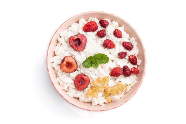 Rice flakes porridge with milk and strawberry in ceramic bowl isolated on white surface