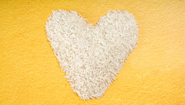 Rice grains shaped like heart on yellow background