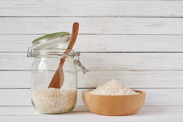 Rice grains in wooden bowl and glass jar