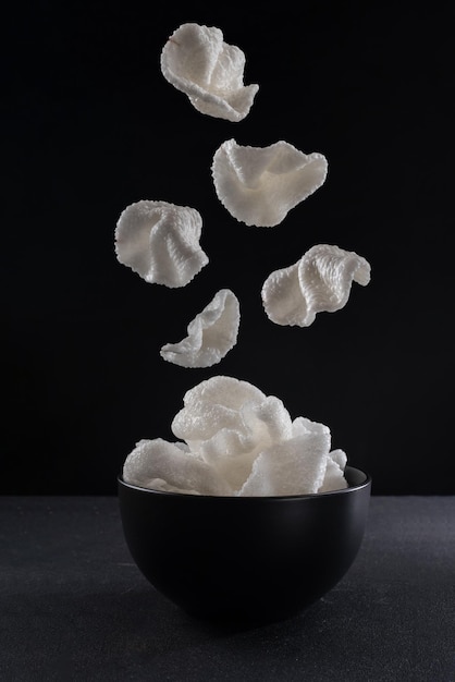 Rice krispies su sfondo nero patatine a levitazione che cadono sul piatto cibo volante