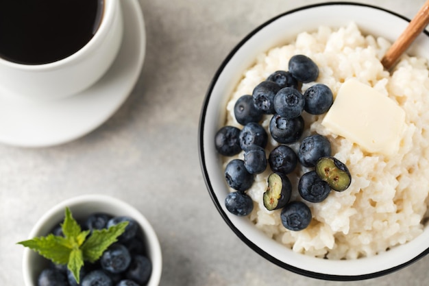 Rice milk porridge with blueberries and a mug of black coffee closeup Healthy breakfast