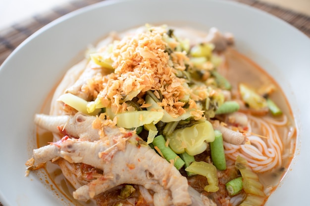 Rice noodles in fish curry sauce with chicken feet.