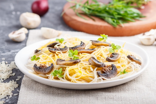 Rice noodles with champignons mushrooms on a black concrete.