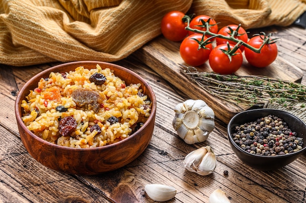 Rice pilaf with lamb meat and vegetables in a wooden bowl