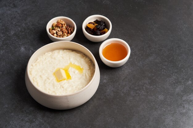 Rice porridge with milk, raisins, honey and nuts in a bowl.