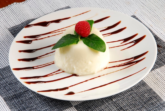 Rice pudding dessert garnished with raspberry plate with lines of liquid chocolate food