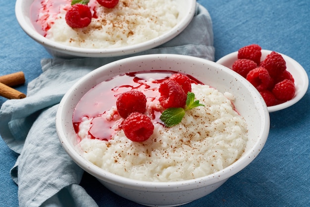 Rice pudding. French milk rice dessert with raspberries, blueberries. Dark background, side view