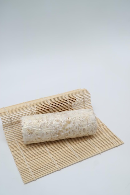 Photo a rice roll wrapped in a plastic wrap sits on a white table.