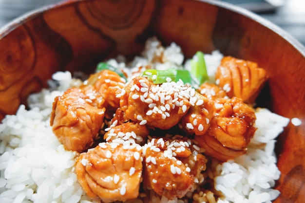 Rice in sauce with stir fried vegetables and salmon in wooden bowl