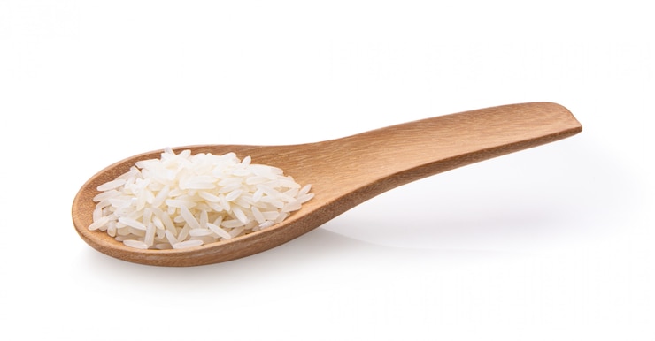 Photo rice seeds in wood spoon  isolated on white background.