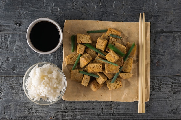 밥, 간장, 젓가락, 구운 두부 치즈 나무 테이블에. 구운 치즈 전채. 평평하다.