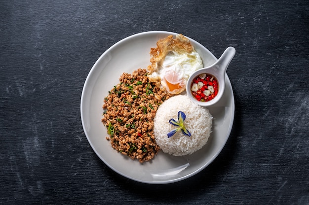 Foto riso condita con carne di maiale saltata in padella e basilico su legno. cibo thailandese