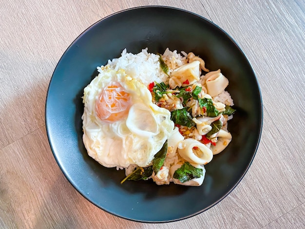 Rice topped with stirfried squid and basil with fried egg