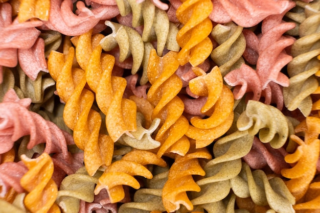 Photo rice vegetable pasta in the form of spirals top view healthy rice pasta with tomatoes selenera carrots and beets