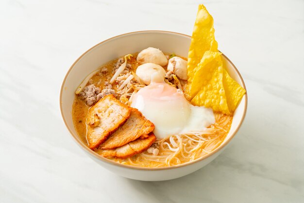 Rice vermicelli noodles with meatball, roasted pork and egg in spicy soup - Tom Yum Noodles