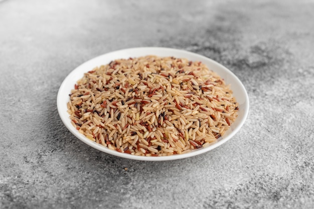 Рис в белом блюдце на сером бетонном фоне