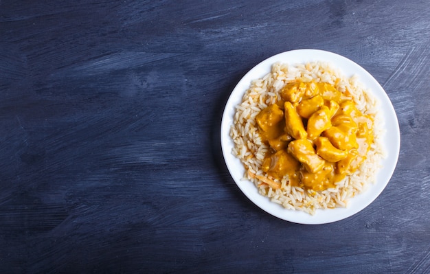 Rice with chicken curry sauce with cashew on black wooden background.