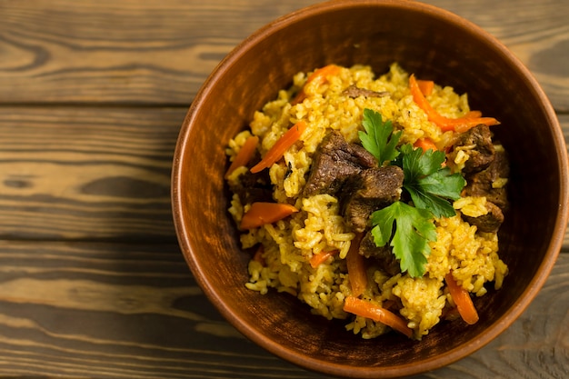 Riso con verdure e carne in un piatto, su un tavolo di legno