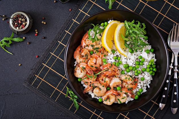 若いグリーンピース、エビ、ルッコラと黒のボウルにご飯。健康食品。仏bowl。上面図。平置き