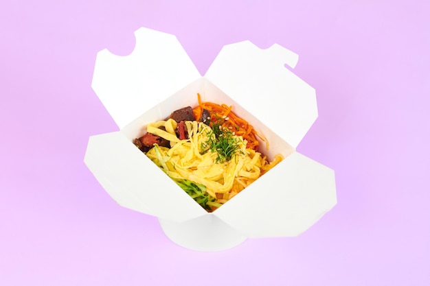 Rice wok with seafood and vegetables in white box isolated on purple background, top view. One open takeout box with rice wok, seafood cocktail and vegetables. Asian food, fast food delivery concept