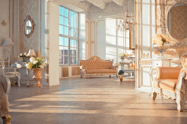 Rich apartment interior with golden baroque decorations on the walls and luxury furniture. the room is flooded with the rays of the setting sun