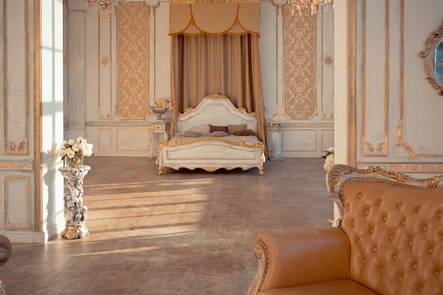 Rich apartment interior with golden baroque decorations on the walls and luxury furniture. the room is flooded with the rays of the setting sun