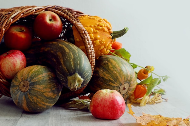 Photo rich autumn harvest ripe vegetables in a wicker basket on a wooden table on a gray background closeup space for text