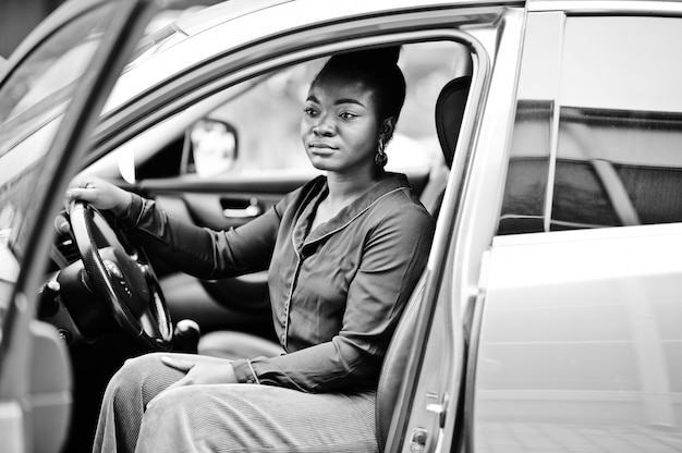 Rich business african woman sit on driver seat at silver suv car with opened door