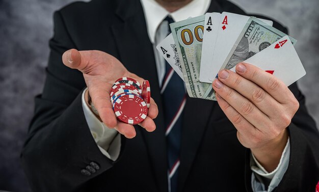 Rich business man holding dollar and play card for poker\
game