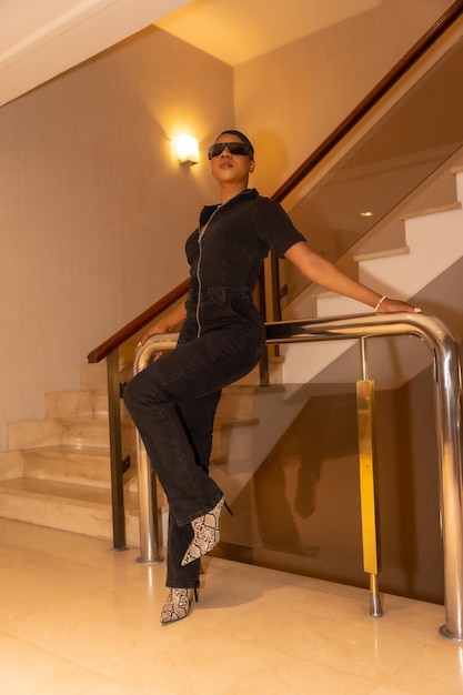 Rich ethnic black woman in sunglasses posing on hotel stairs luxury concept