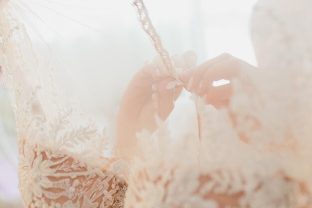 Foto il ricco abito da sposa rosa è appeso a un lampadario in una stanza bianca