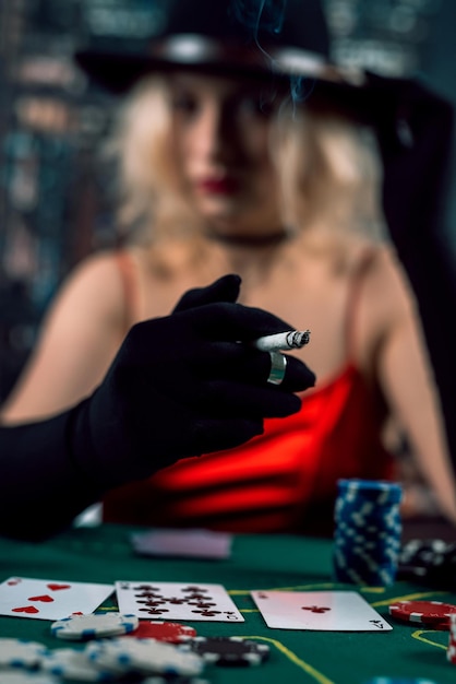 Rich woman wear evening red dress playing poker holding cigar