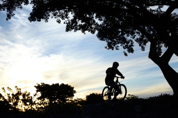 夕暮れ時に自転車に乗る男のシルエットショットに乗る