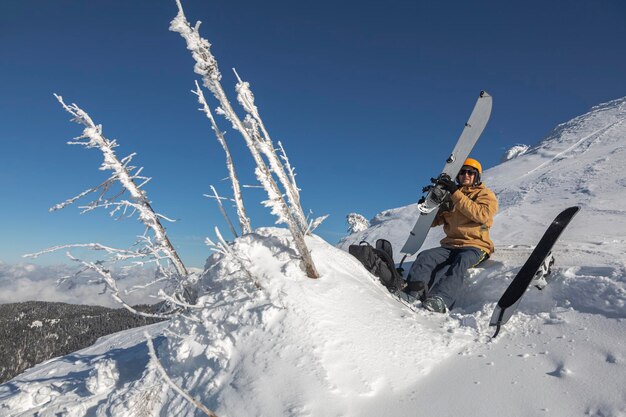 雪山の背景にスキー ヘルメットのスプリット ボードを持つライダー