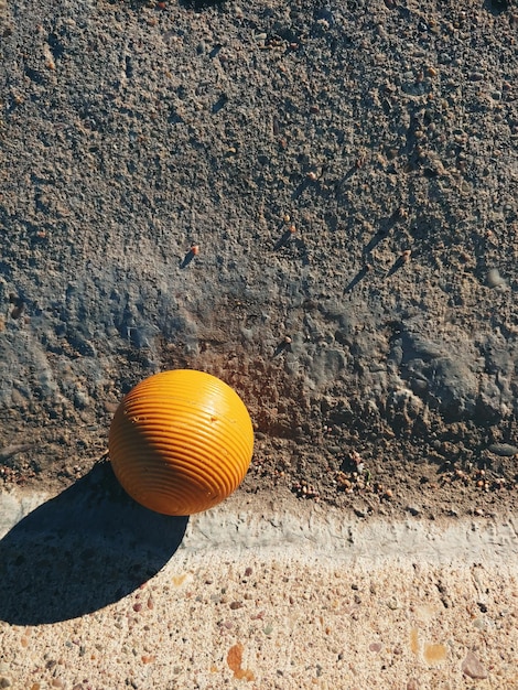 Foto palla gialla a righe alla luce mattutina sul cemento