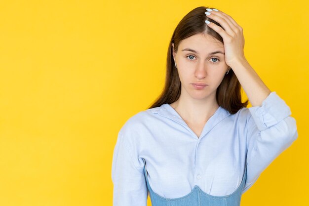 Ridiculous situation Confused woman Disbelief emotion Embarrassed lady holding head with hand feeling epic fail isolated yellow copy space