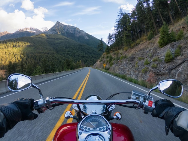 Foto in sella a una moto su una strada panoramica circondata dalle montagne canadesi