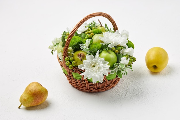 Rieten mand gevuld met fruit en witte bloemen, evenals een peer en een appel