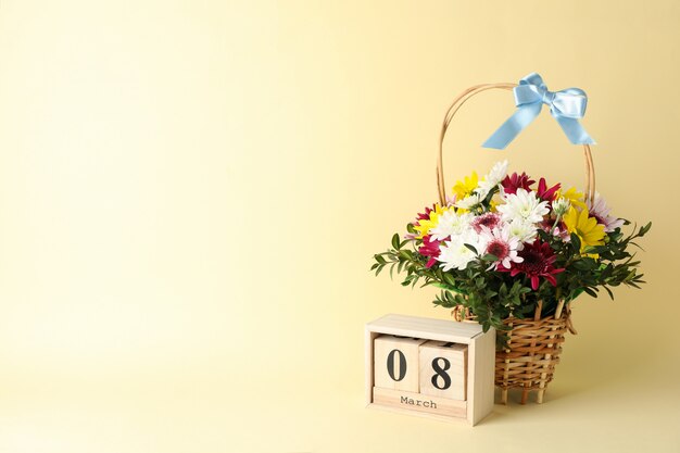 Rieten mand met bloemen en houten kalender op beige