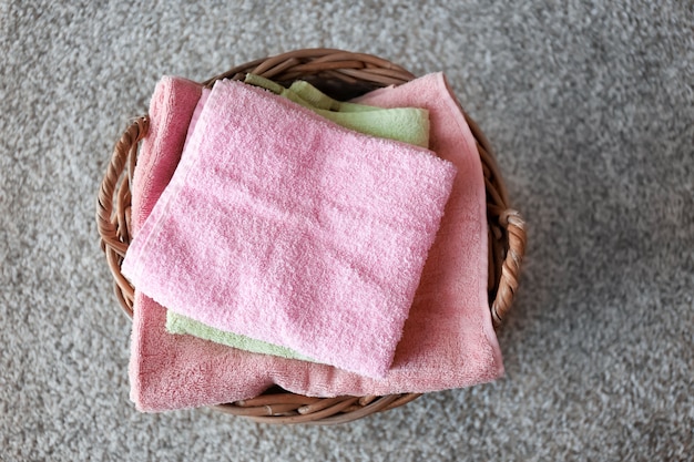 Rieten mand met gevouwen schone handdoeken op vloer