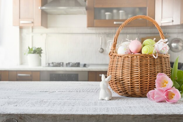 Rieten mand met konijntje, tulp, kleurrijke eieren van Pasen op keuken houten tafel. Lente Pasen samenstelling.