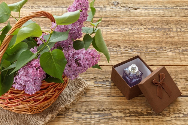 Rieten mand met lila bloemen en een geschenkdoos op houten planken