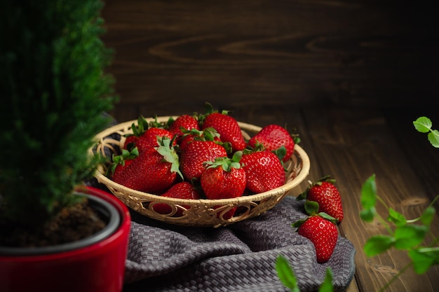 Rieten mand met zoete rode aardbeien op een donkere houten tafel