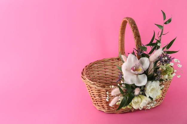 Rieten mand versierd met prachtige bloemen op roze achtergrondruimte voor tekst Pasen-item