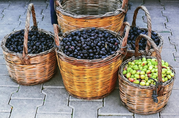 Rieten manden vol groene en zwarte olijven staan buiten op straatstenen Straatvoedselmarkt in Turkije
