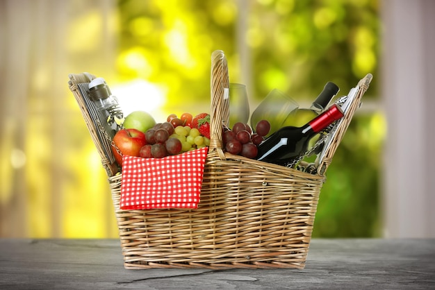 Rieten picknickmand met wijn en verschillende producten op zwarte leisteen tafel binnenshuis